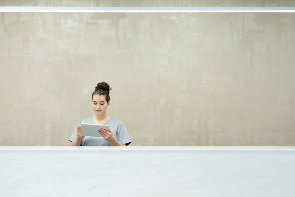 Receptionist at a front desk holding a tablet