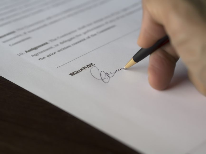 Hand signing a contract with a pen