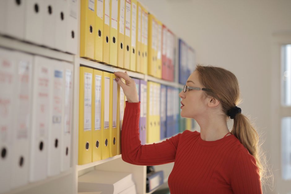 Person pulling a binder from a shelf of files