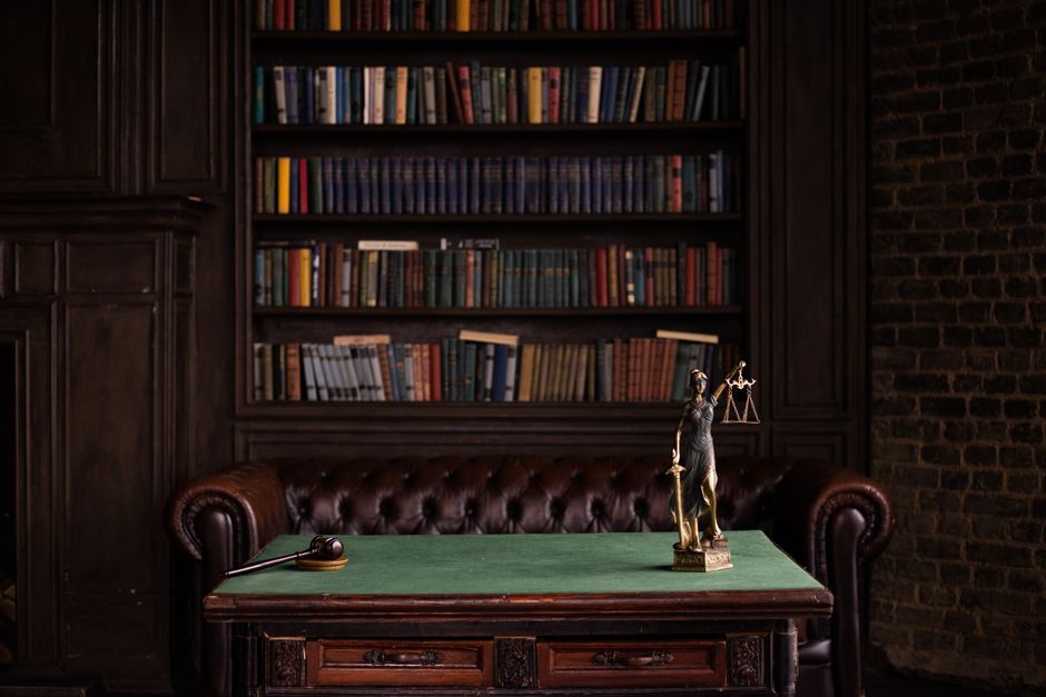 Law books and a scales of justice statue in an office