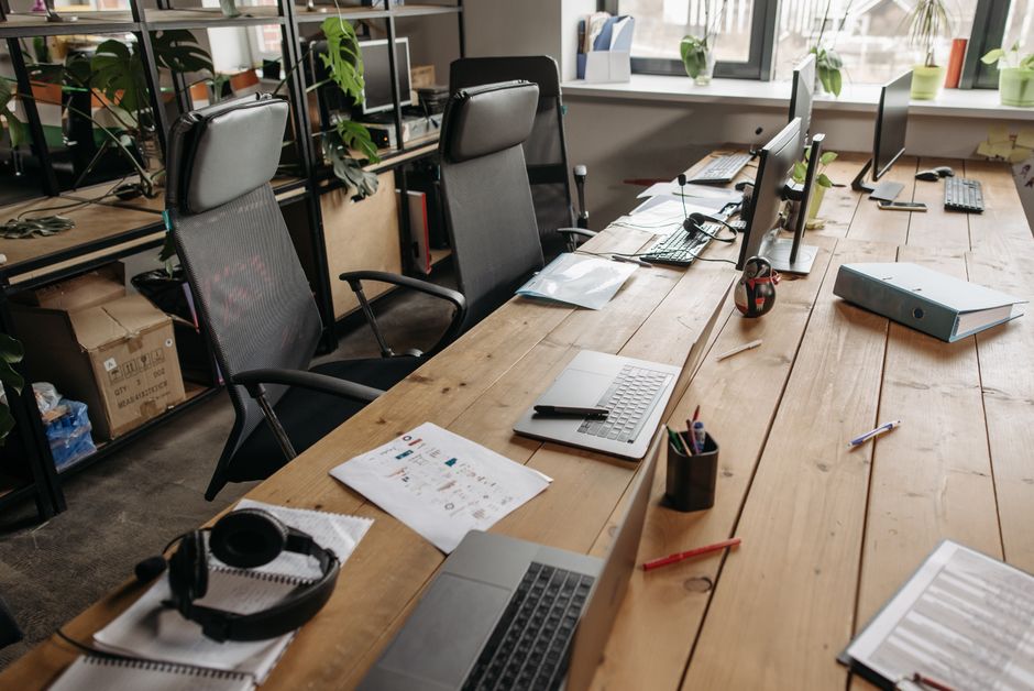 Laptops and monitors along a long office desk